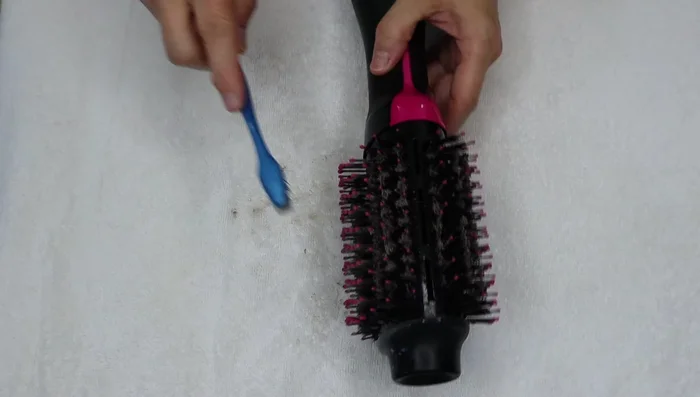 Use an old toothbrush to scrub the bristles, working from the base to the tips and at various angles. Be prepared for splattering.