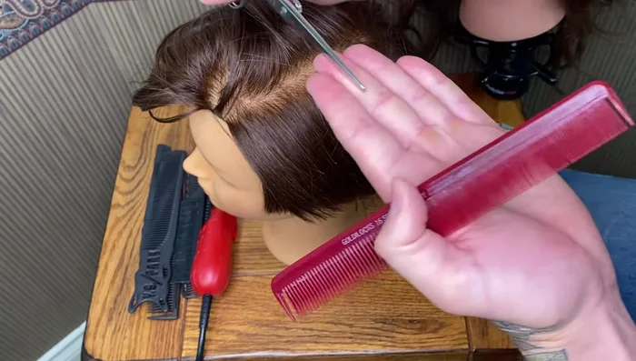 Hold the scissors perpendicular to your hand, with the blade resting on your finger.