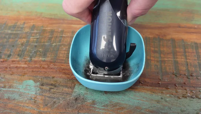 Submerge clippers in clipper side spray to remove built-up hair and gunk (repeat as necessary).