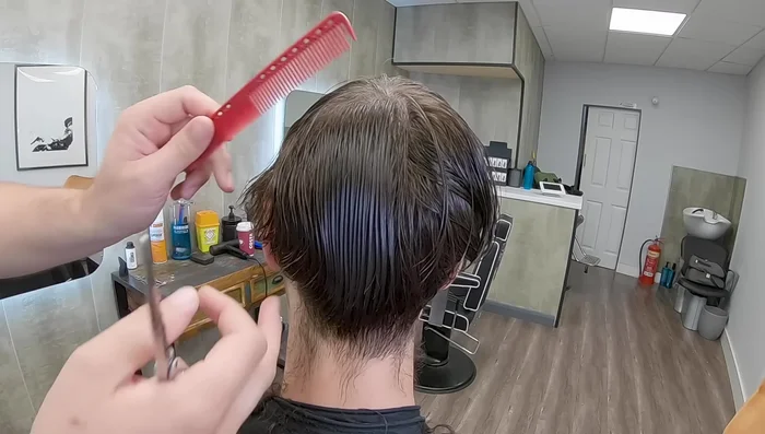 After cutting the lower sections, pull down the long hair that was initially moved out of the way and create a clean line from the crown to the ear.