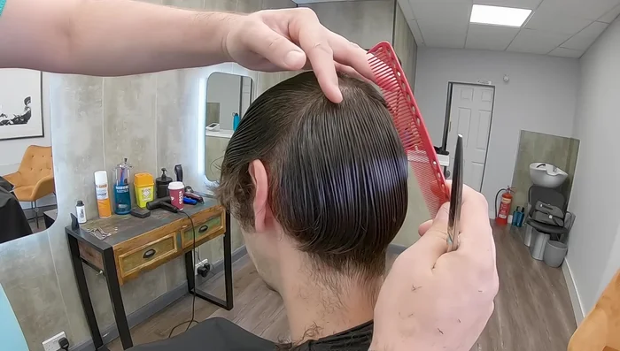 Take sections from the crown downwards, guiding the cut by the already cut short hair to create a graduation.