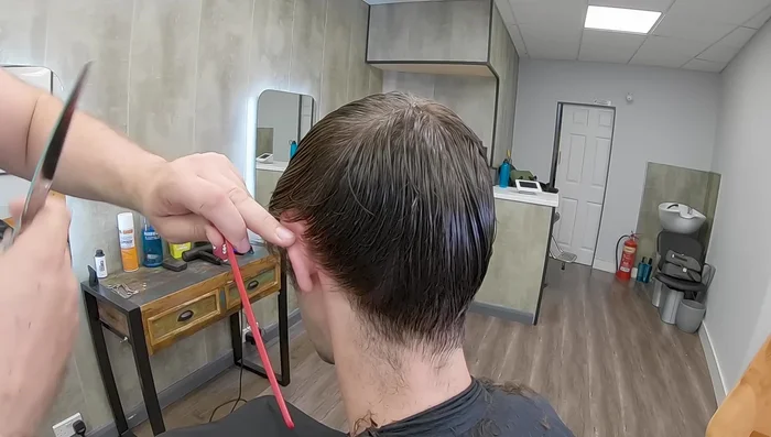 Pull the hair towards the ear and cut downwards to create a clean hairline that won't stick out.