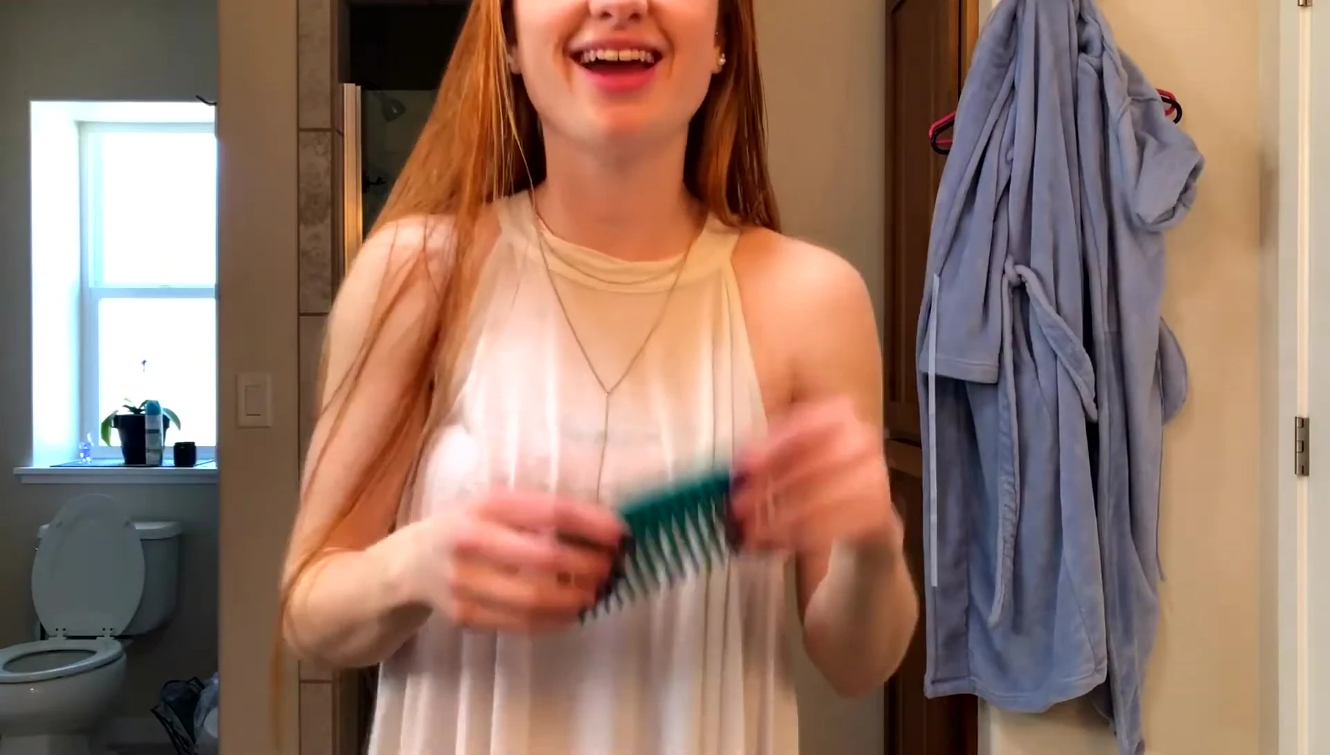 The vlogger using a wide-tooth comb on wet hair.