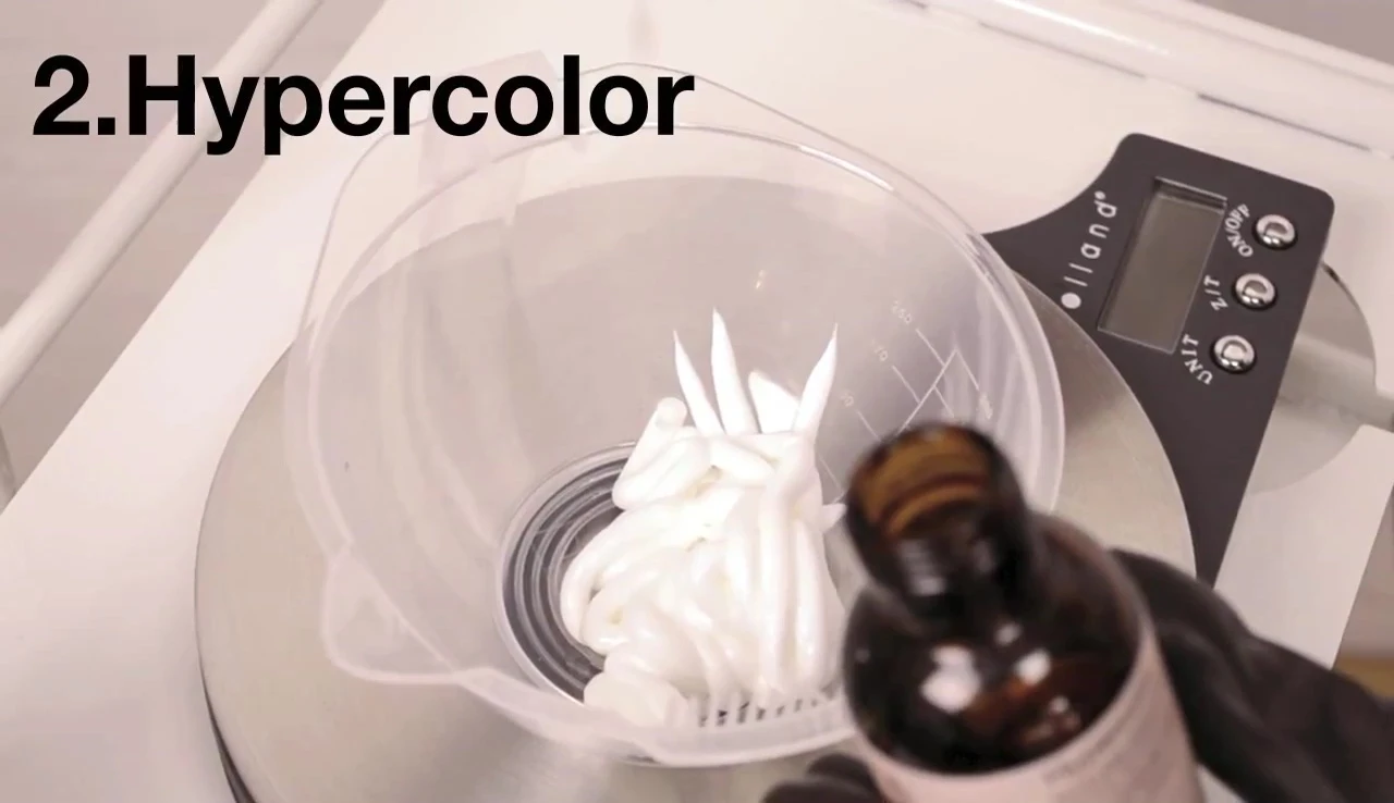 Close-up view of the hair color being applied to a strand of hair.