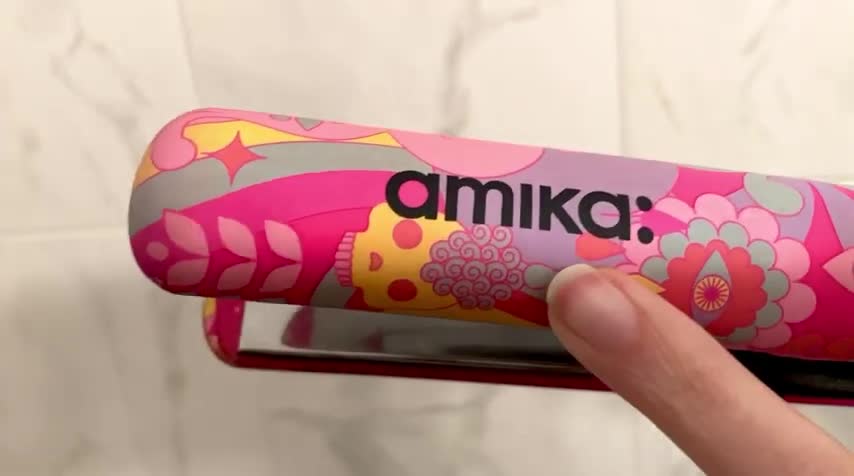 Close-up shot of the Amika hair straightener in hand, showcasing its size and shape.