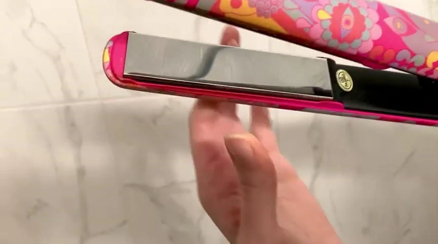 Hand holding the straightener, highlighting the placement of the dials.