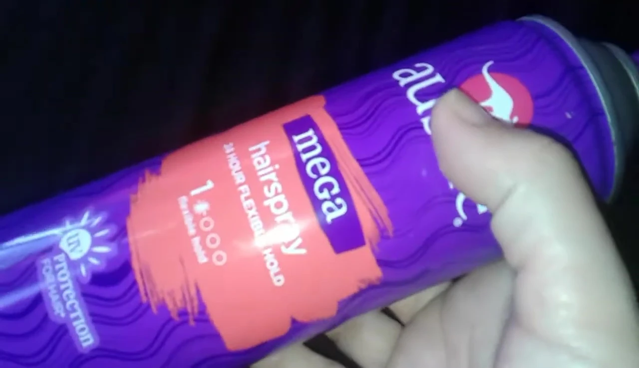 The reviewer displaying a large can of the hairspray.