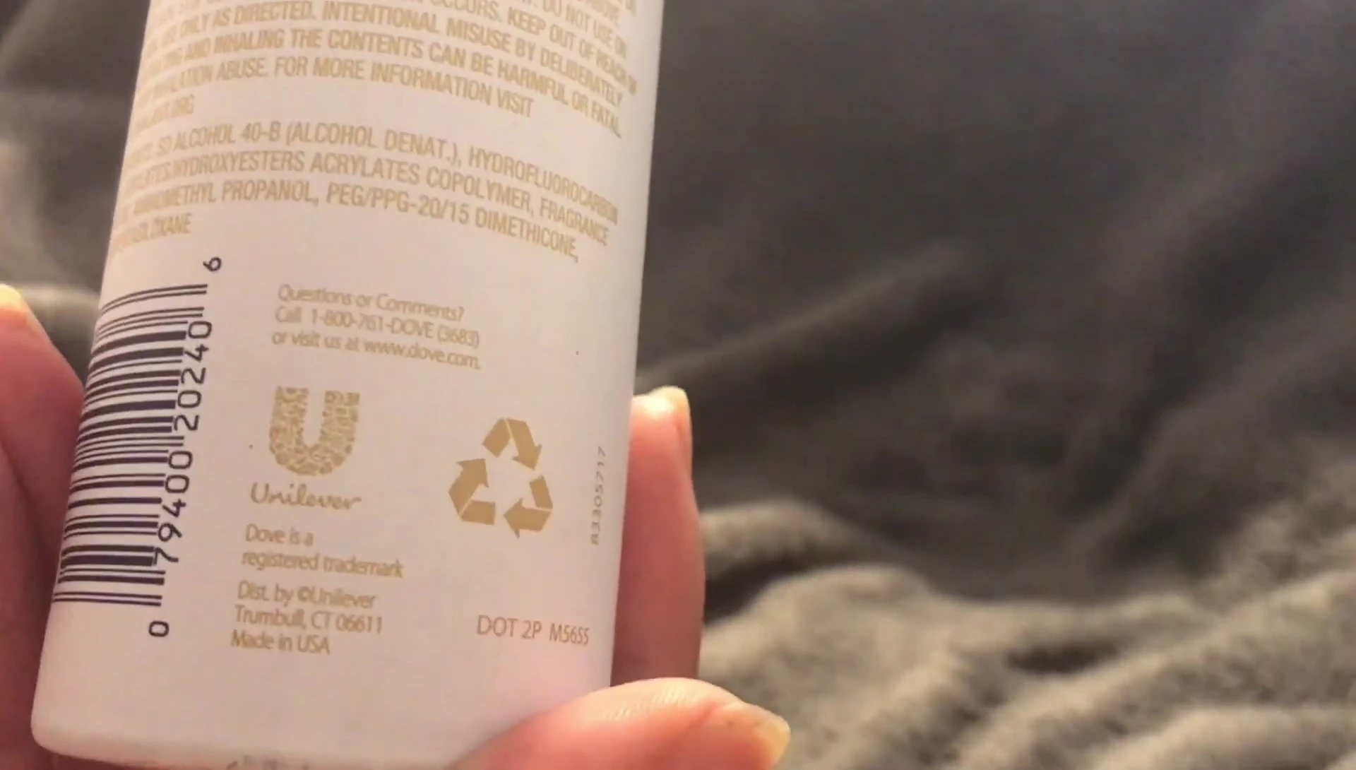 The reviewer showcasing the Dove Style Care hairspray bottle.