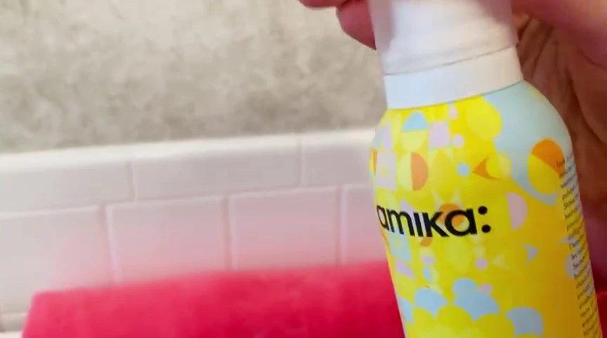 Person applying the spray to their hair.