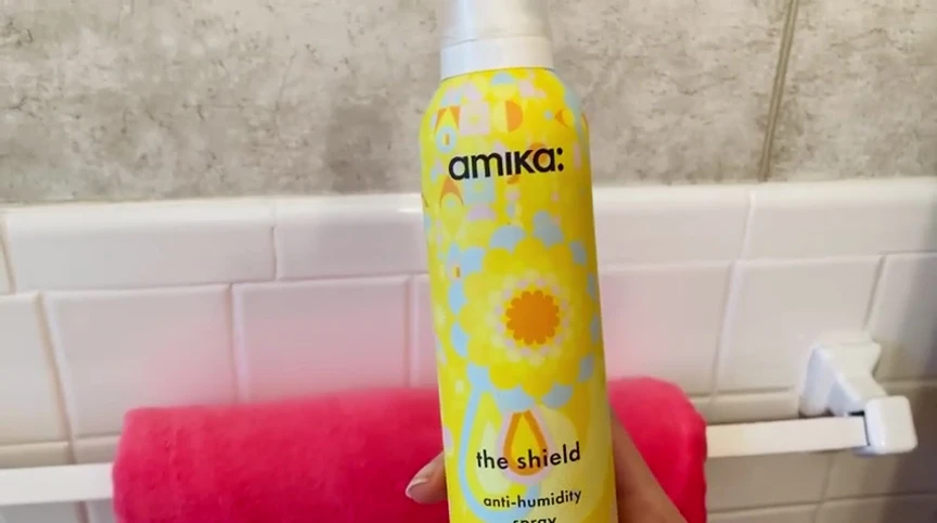Person spraying their hair and the hair looking sleek and shiny.