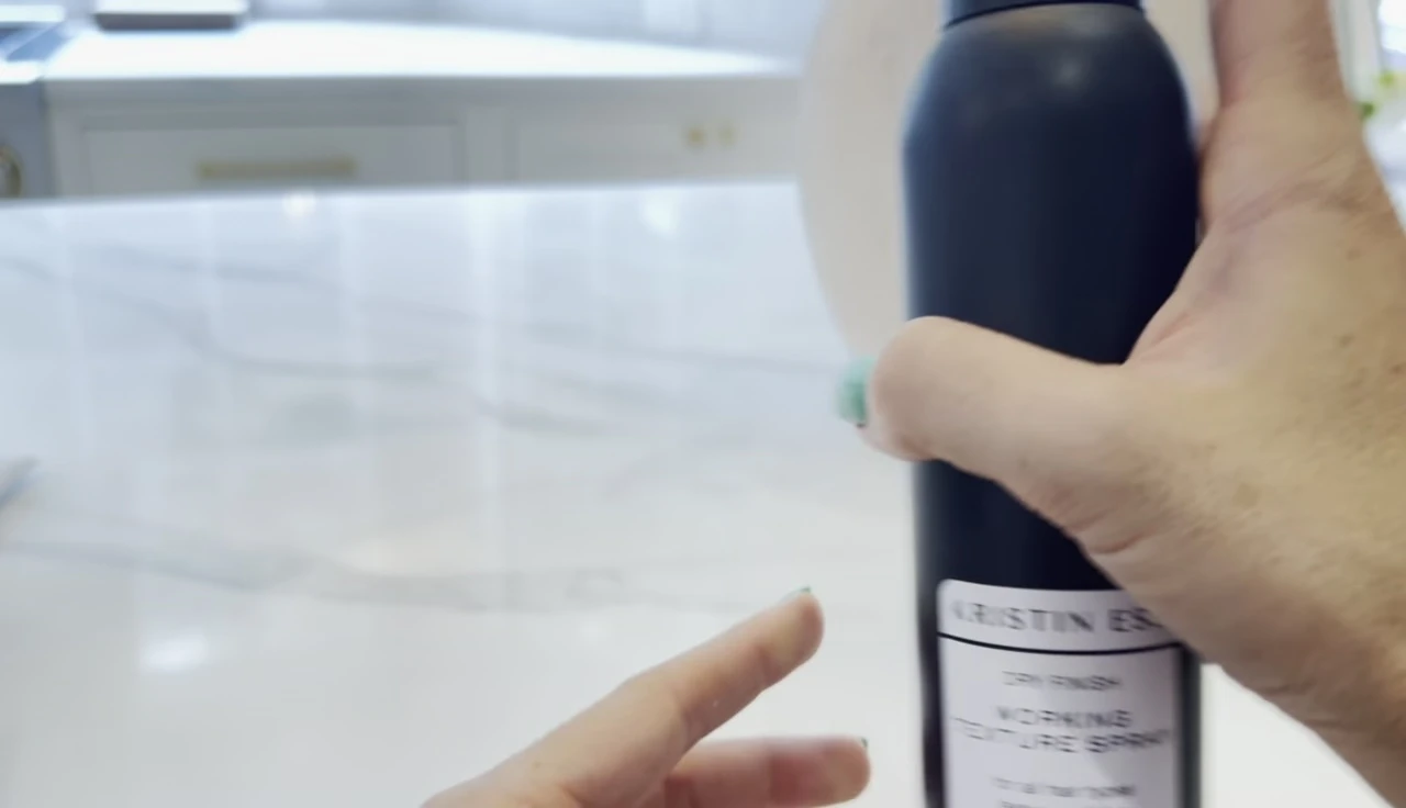 The fine mist of the spray being applied to hair.